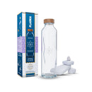 Botella de cristal programado junto a su caja Energy Flow y piedras blancas apiladas para bienestar.